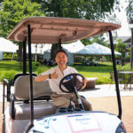 A Macalester staff member smiles and gives a thumbs up from the driver's seat of a golf cart