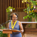An alum with a yellow medal speaks at a podium