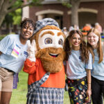 Three Reunion student workers pose with Mac the Scot