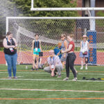 A team of alumni slingshot a water balloon across a football field