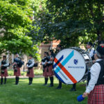 The Macalester Pipe Band playing outside with a close-up on a drummer