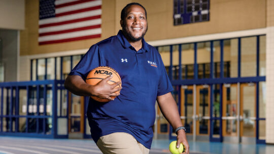 Donnie Brooks holds a basketball in one hand and a tennis ball in the other