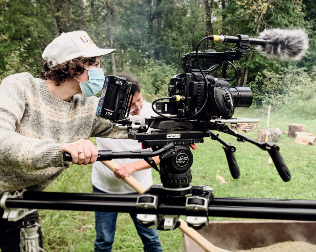 A filmmaker controls a camera in a forested area