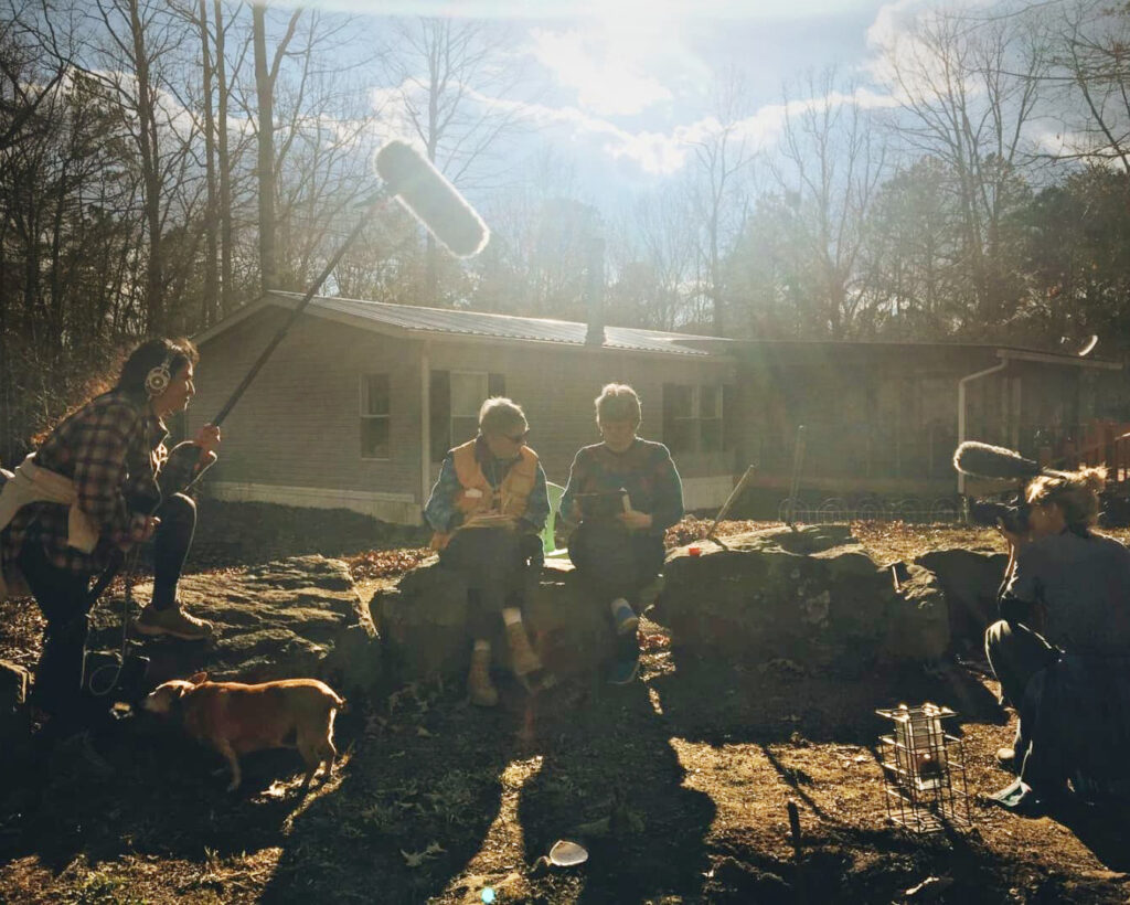 Filmmakers record two subjects sitting on the ledge outside of a home