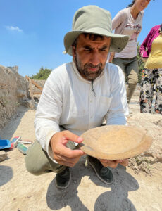 Dr. Serdar Yalcin at an archaeological dig, examining an ancient pot
