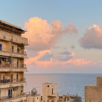 Egypt at sunset, with buildings with balconies in the foreground and the sea in the background