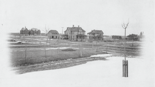 Historic 1889 photograph of Macalester College campus showing Old Main in the distance and faculty houses along Summit Avenue, with dirt roads and sparse tree plantings in the foreground.