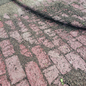Close-up view of 1800s fired brick street surface uncovered on Grand Avenue during 2025 roadwork.