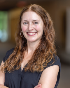Professor Kelly MacGregor smiles while standing in a hallway.
