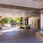 A wide view of the DeWitt Wallace Library entrance, pillars on either side of the photo and a group in the distance walking toward the library