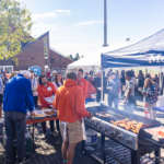 Volunteers grill hot dogs and burgers at the M Club Cookout during Mac Fest 2025.