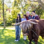 Students and guests pose with Hartnett the mini Highland Coo on the Great Lawn during Mac Fest 2025.
