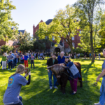 A crowd lines up on the Great Lawn as attendees take photos with Hartnett the mini Highland Coo during Mac Fest 2025.