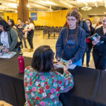 Kao Kalia Yang hands an autographed book to a student in line at her signing table