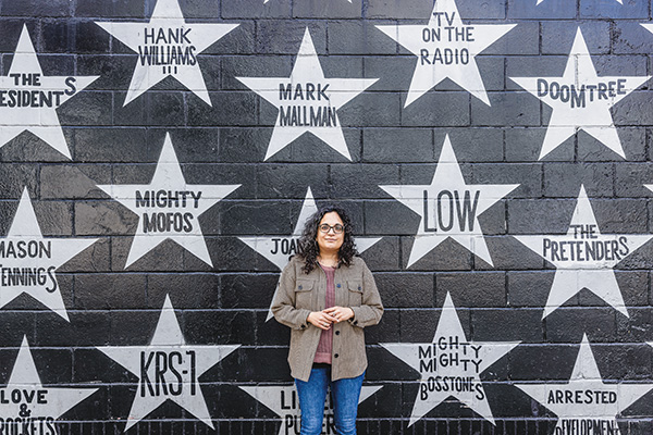 Sonia Turner stands in front of a wall painted with stars at First Ave