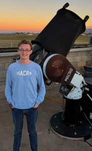 Jackson Codd '23 standing beside a telescope