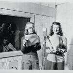 Two students hold pieces of paper and speak into a 1960s microphone