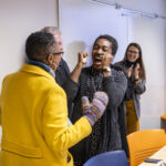 Executive Vice President and Provost Lisa Anderson-Levy celebrates with Professor James, who has two hands raised in celebration.
