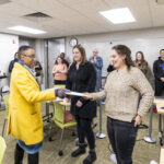Executive Vice President and Provost Lisa Anderson-Levy hands a tenure award folder to Professor Flock.