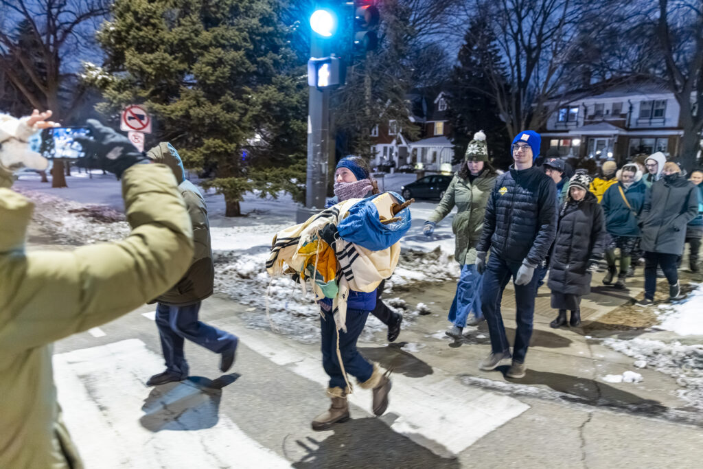 Lia Grant '24 carries Macalester's new Torah in a procession towards the Weyerhaeuser Memorial Chapel.