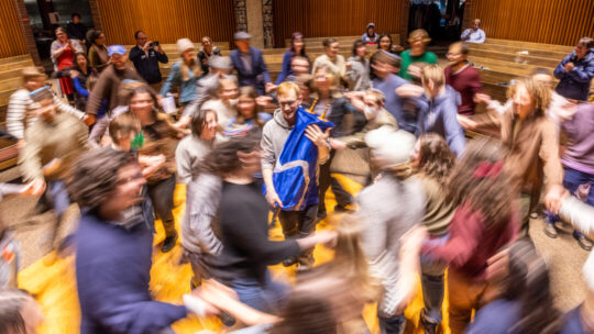 Louis Hunter '18 holds Macalester's new Torah while attendees at a Torah Welcoming Ceremony dance around them.