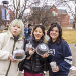 Three students pose for the camera, two of them holding boxed cakes