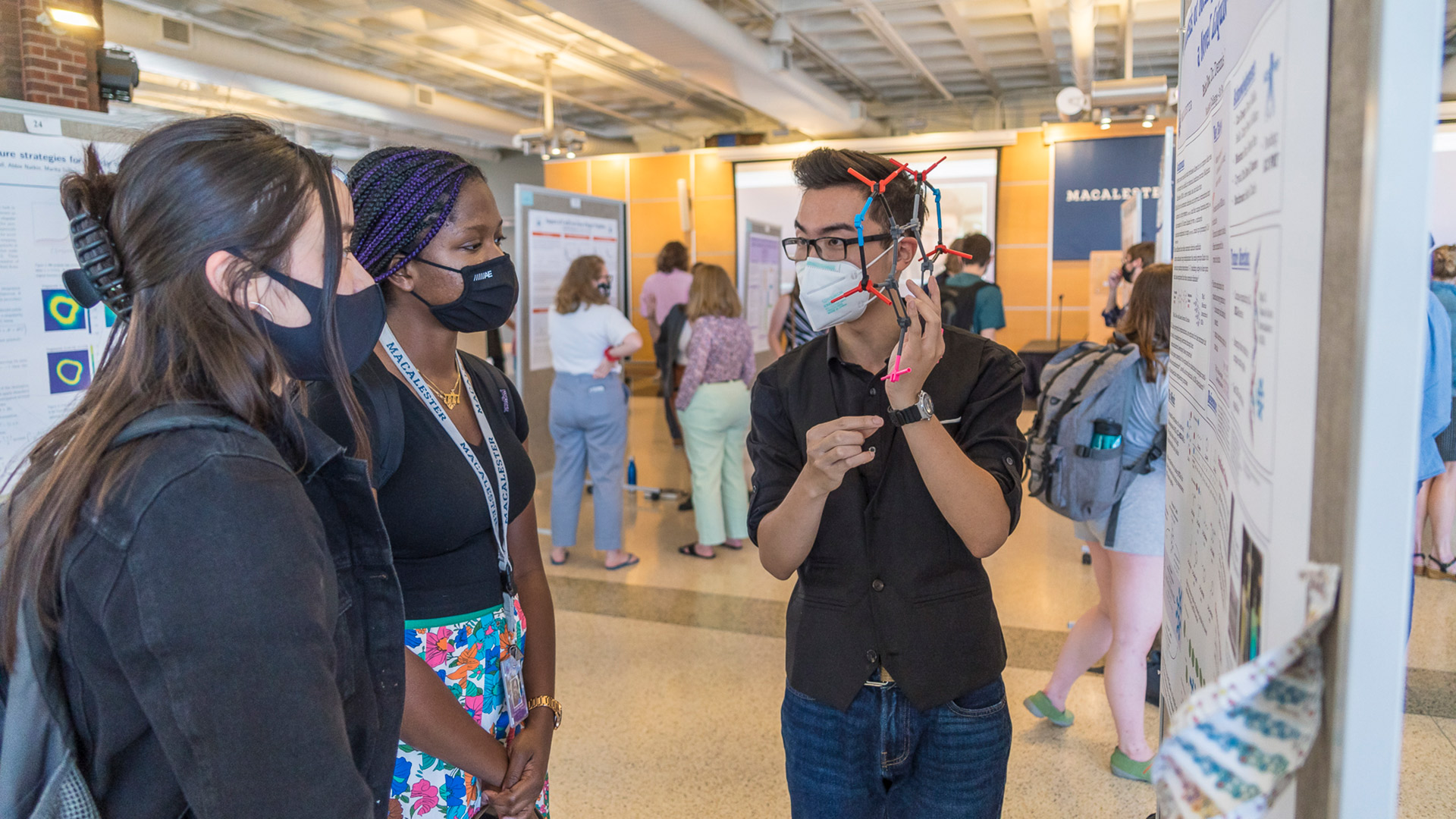 Student presenting research poster to other students in Kagin Commons.