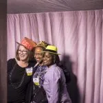 Three alumni posing at a photo booth
