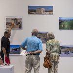 Professor showing art to two alumni