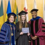 A graduating student poses with President Suzanne Rivera and Provost Lisa Anderson-Levy at Macalester's 2022 December Graduation.
