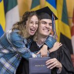 A graduating student poses with another person at Macalester's December 2022 graduation ceremony.