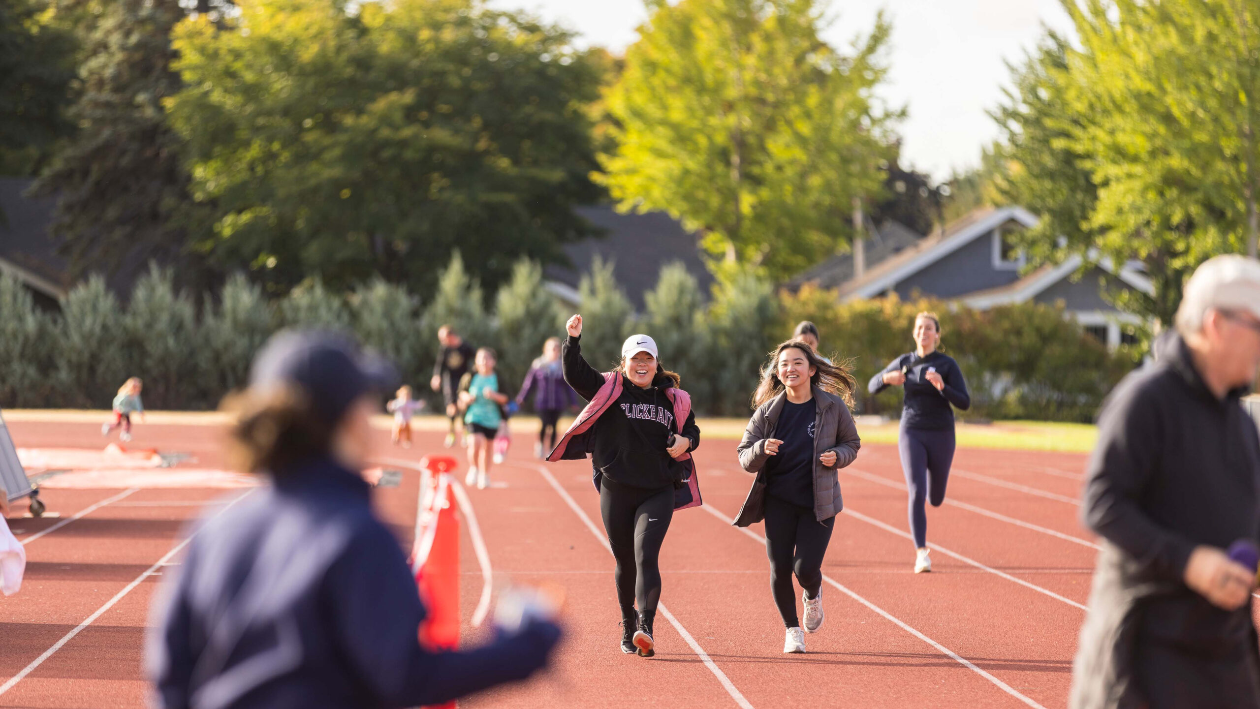 Two students run and cheer on the track at the Mac Fest 5K