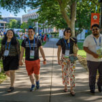 Four alumni walking down a path smile for the camera