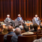 Former Macalester presidents Robert Gavin, Brian Rosenberg and Michael McPherson and current president Suzanne Rivera sit in chairs lined up on a stage