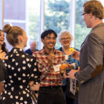 Seven Reunion attendees stand together in Kagin Ballroom talking and smiling