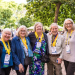 Five alumni wearing Golden Scots medals stand in a line smiling