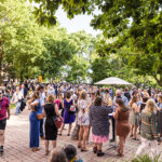 A large group of Reunion attendees mingles together at a courtyard