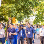 A group of alumni walk down a path behind a 1999 sign