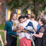 Four Reunion attendees greet each other while smiling. Two give each other a hug