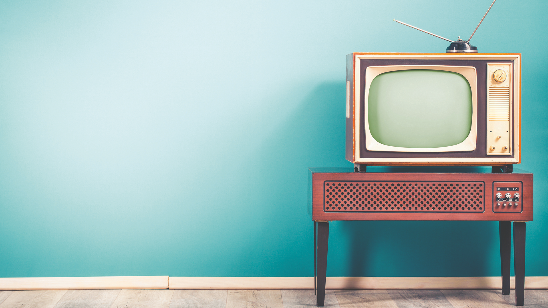 A 1950s-era TV set sits on top of a vintage wood speaker set