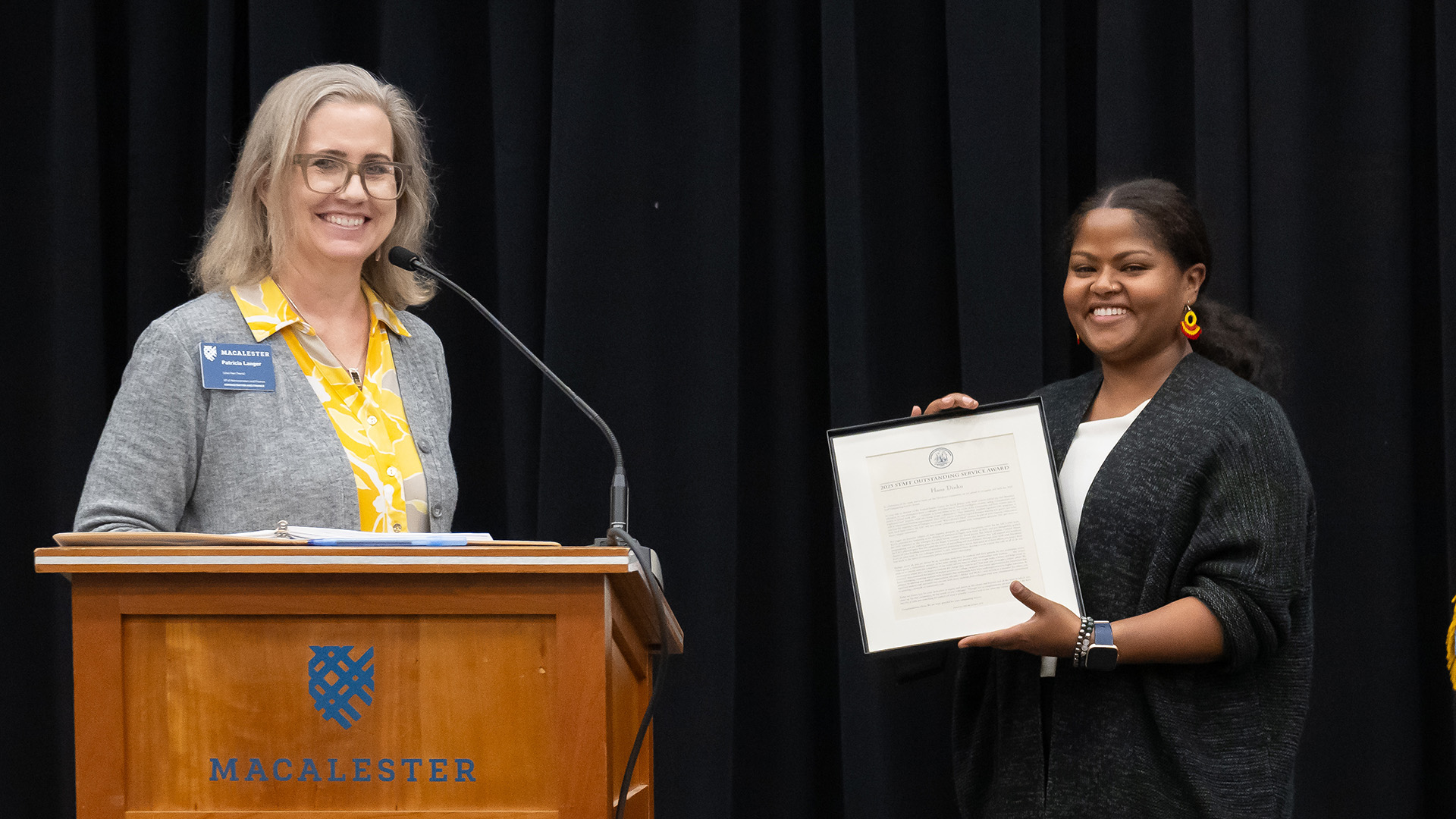 Hana Dinku holds her 2025 Staff Outstanding Service Award. Vice President of Administration and Finance Patricia Langer stands next to her.