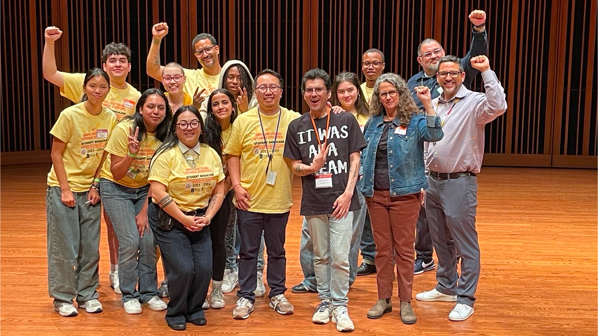 Macalester student Marco Lopez ’27 poses with a group of peers and mentors on stage, smiling and raising their fists to celebrate.