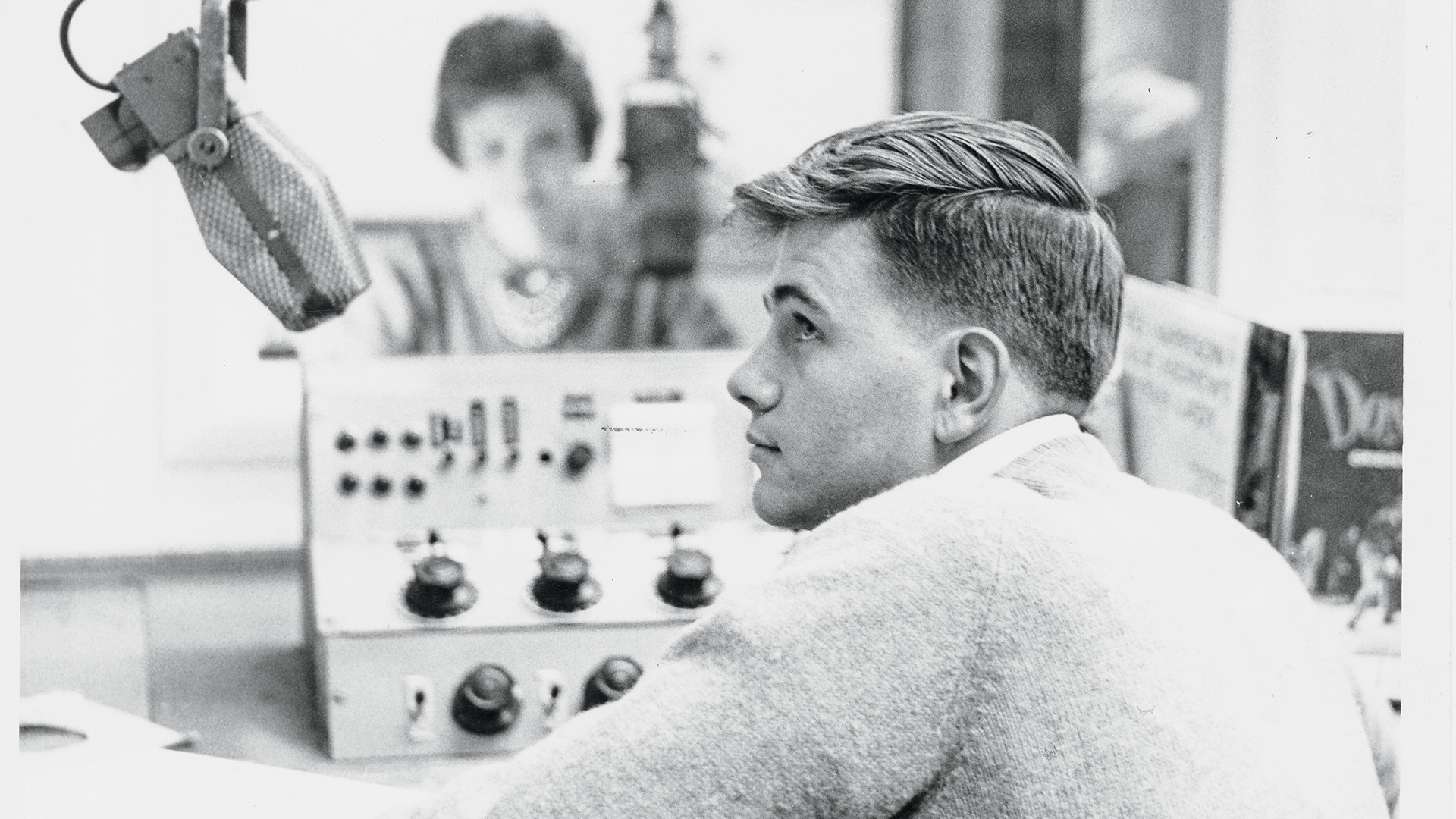A 1960s photo of two students sitting in a radio booth and speaking into microphones