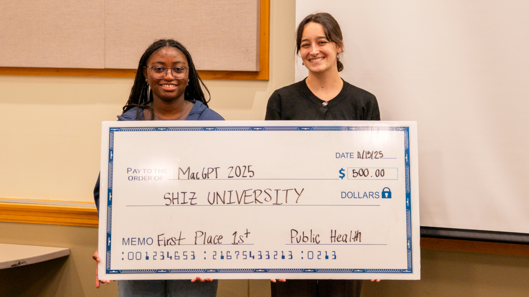 Two students hold a large check for $500