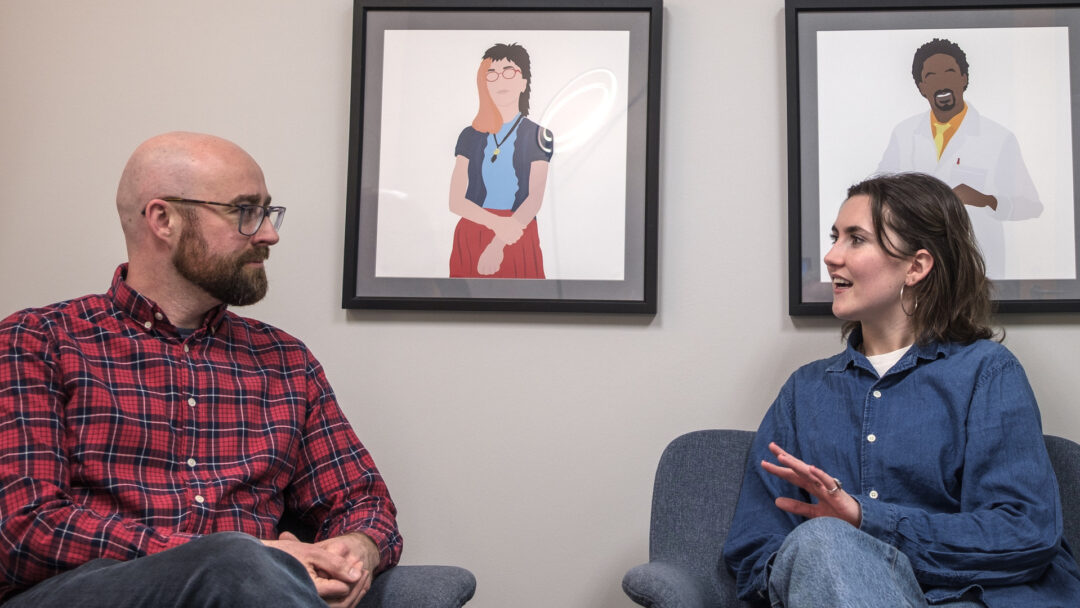 Matt Kazinka ’11 and Caroline Fitzpatrick '26 sit next to each other and talk to each other