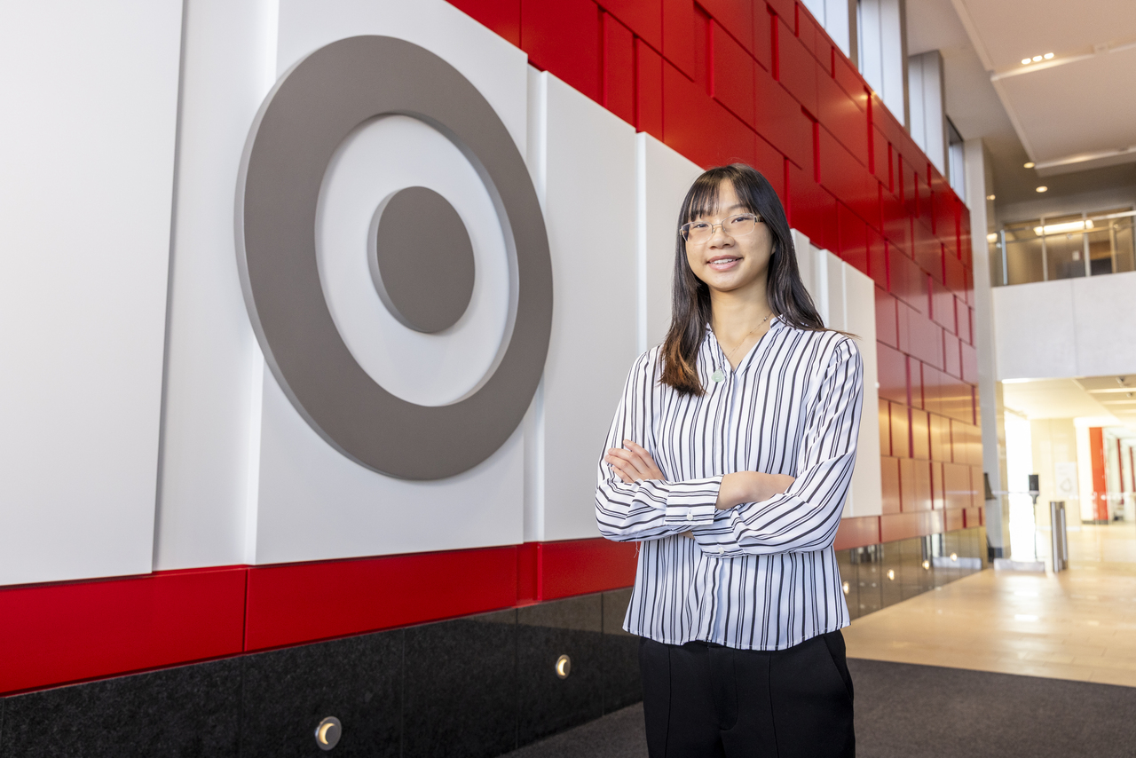 Target fellow Lilly Lu ’25 poses for a photo in the lobby of her Target office. A large Target logo appears on a wall behind her.