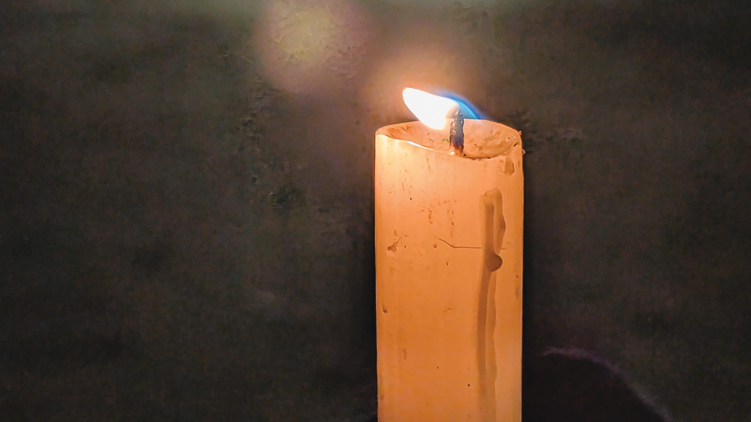 A candle lit in a dark background