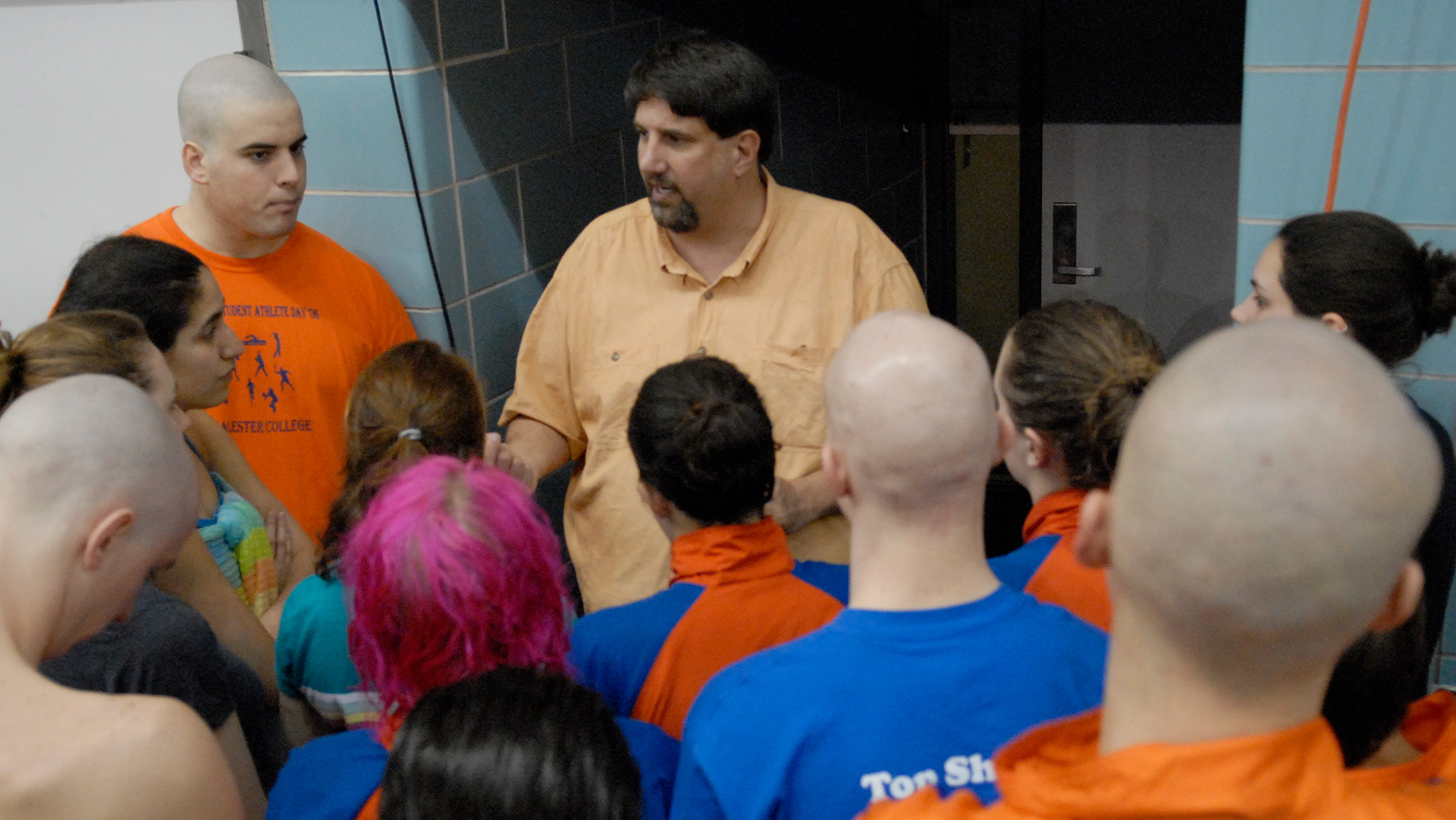 A coach talks to a group of swimmers gathered in a circle around him