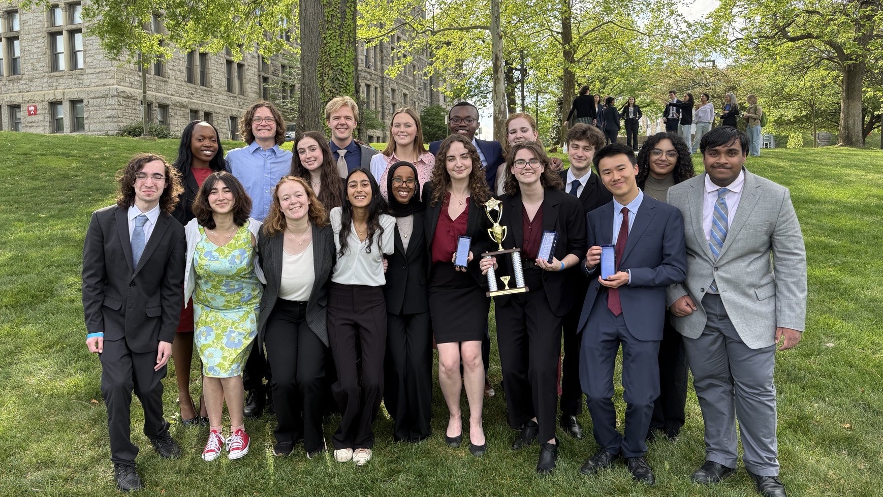 All members of Macalester's collegiate mock trial program pose together outside on a grassy lawn.