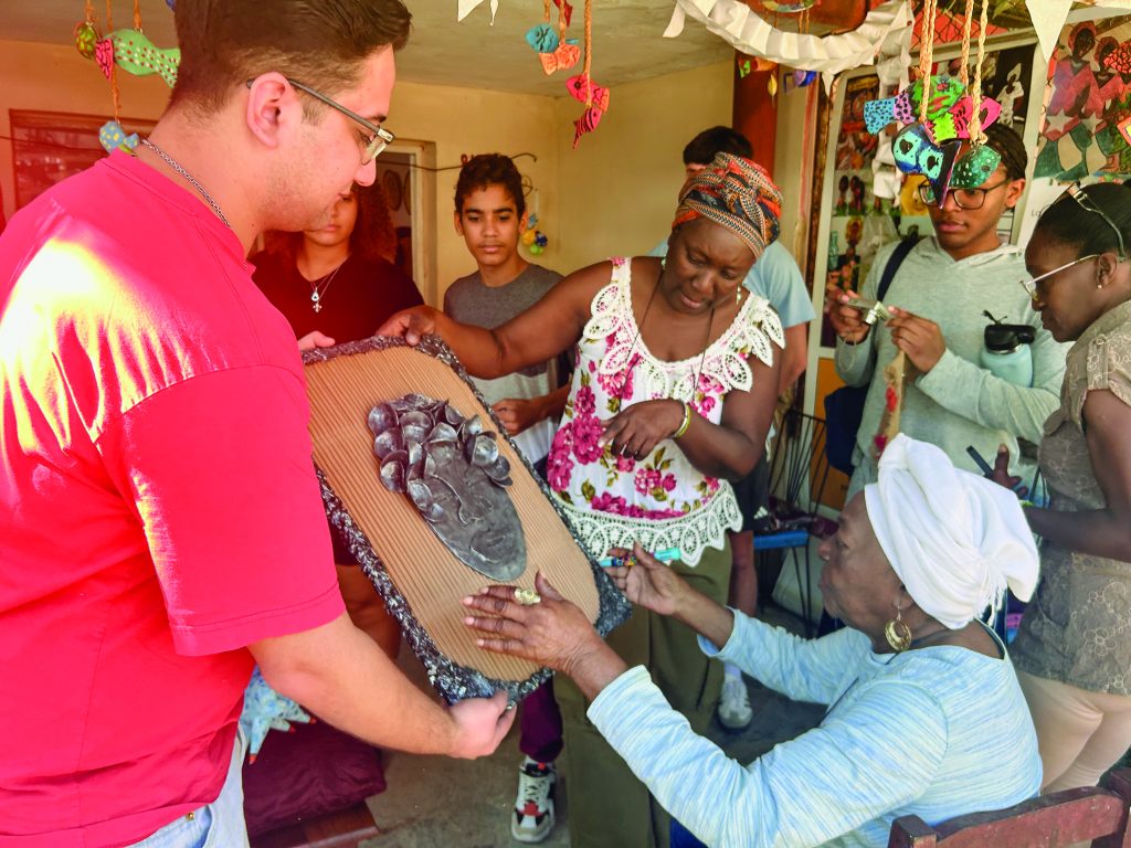 At La Muñeca Negra, Guillermo Muñoz-Calanche ’28 holds artwork the Macalester students purchased together to donate to the Cultural House—a gift for future C-House residents, signed by the artist.